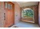 Covered front porch with a hanging swing, wood door and brick archway at 1278 Dexter St, Denver, CO 80220