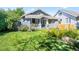 Charming blue bungalow with a well-manicured lawn and lush flowerbeds leading to the front door at 4429 Winona Ct, Denver, CO 80212