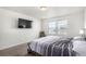 Bright bedroom featuring neutral tones, a large window, wall-mounted TV, and a comfortable bed with striped comforter at 803 N Bently St, Watkins, CO 80137
