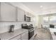Galley kitchen offers gray cabinets, stainless steel appliances, and views to dining area at 803 N Bently St, Watkins, CO 80137