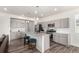 Bright kitchen boasts gray cabinets, an island with bar seating, and stainless steel appliances at 803 N Bently St, Watkins, CO 80137