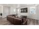 Modern living room with a large brown leather sofa, hardwood floors, and a wall-mounted TV at 803 N Bently St, Watkins, CO 80137