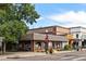 Brick building with charming storefront windows and a tiled roof, surrounded by lush trees and sidewalks at 1451 S Columbine St, Denver, CO 80210