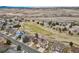 An aerial view shows the community backing to open space with a putting green, the mountains, and a highway at 401 W Prestwick Way, Castle Rock, CO 80104