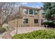 The back of the house features a tan exterior, large windows, and a cement patio surrounded by greenery at 401 W Prestwick Way, Castle Rock, CO 80104