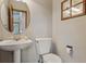 Half bath featuring a pedestal sink, rounded mirror and wood accents at 401 W Prestwick Way, Castle Rock, CO 80104