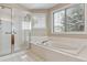 Bathroom featuring clear glass shower, white bathtub with tile surround and window view at 401 W Prestwick Way, Castle Rock, CO 80104
