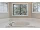 Bright bathroom featuring soaking tub with white tile surround and view from the window at 401 W Prestwick Way, Castle Rock, CO 80104