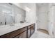 Bathroom featuring double sinks, a white countertop, and a tiled shower with glass door at 8517 Eckley St, Littleton, CO 80125
