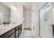 Bathroom featuring double sinks, a white countertop, and a tiled shower with glass door at 8517 Eckley St, Littleton, CO 80125