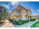 Charming yellow two-story townhome exterior with well-kept landscaping and inviting front porches on both floors at 9585 Pearl Cir # 203, Parker, CO 80134