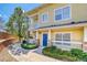 Inviting yellow townhome with a blue front door, stone accents, and a well-maintained walkway and landscaping at 9585 Pearl Cir # 203, Parker, CO 80134