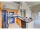 Kitchen featuring wooden cabinets, black appliances, and an island with bar seating, with view of stairwell at 9585 Pearl Cir # 203, Parker, CO 80134
