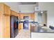 Kitchen featuring wooden cabinets, black appliances, and an island with bar seating, with view of stairwell at 9585 Pearl Cir # 203, Parker, CO 80134