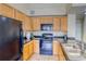 Kitchen featuring wooden cabinets, black appliances, and an island with stainless steel sink, and updated flooring at 9585 Pearl Cir # 203, Parker, CO 80134