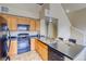 Kitchen featuring wooden cabinets, black appliances, and an island with stainless steel sink, close to entry at 9585 Pearl Cir # 203, Parker, CO 80134