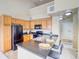 Well-lit kitchen with wooden cabinets, black appliances, and an island with bar seating, with view into entry at 9585 Pearl Cir # 203, Parker, CO 80134