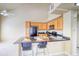 Bright kitchen featuring wooden cabinets, black appliances, and an island with bar seating and a stainless sink at 9585 Pearl Cir # 203, Parker, CO 80134