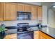 Features a black electric stove, black countertop, and wooden cabinets at 9585 Pearl Cir # 203, Parker, CO 80134