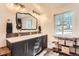 Bathroom featuring double sinks, black vanity, unique mirror, and open shelving, filled with natural light at 30690 Highway 72, Golden, CO 80403