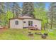 Charming tan home exterior with a cozy deck, grill, and fire pit surrounded by lush greenery at 30690 Highway 72, Golden, CO 80403