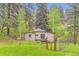 Charming tan home exterior with a cozy deck, secured by a wire fence, surrounded by lush greenery at 30690 Highway 72, Golden, CO 80403