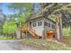 Charming home featuring a wooden porch and stairs, complemented by a matching dog house, set amongst mature trees at 30690 Highway 72, Golden, CO 80403