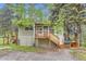 Cozy home with a wooden porch, complemented by a charming dog house, nestled among vibrant trees and a gravel driveway at 30690 Highway 72, Golden, CO 80403