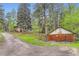 Scenic view of a hillside home with a detached garage, accessible via a gravel driveway amid lush trees and greenery at 30690 Highway 72, Golden, CO 80403