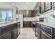 Bright, open kitchen boasts stainless appliances, dark wood cabinets, white countertops, and subway tile backsplash at 14127 Deertrack Ln, Parker, CO 80134
