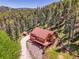 Expansive aerial view showcases the house, driveway, and surrounding dense forest, creating a private retreat at 11768 Black Hawk Dr, Conifer, CO 80433