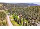 Breathtaking aerial shot of a secluded home surrounded by lush forest and a serene pond, creating a peaceful retreat at 11768 Black Hawk Dr, Conifer, CO 80433