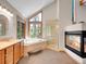 Bright bathroom featuring a soaking tub, glass shower, and a fireplace at 11768 Black Hawk Dr, Conifer, CO 80433