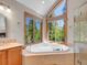 Elegant bathroom with large soaking tub and views of the trees outside at 11768 Black Hawk Dr, Conifer, CO 80433