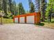 Spacious three-car garage with gravel driveway, perfect for car enthusiasts or extra storage space at 11768 Black Hawk Dr, Conifer, CO 80433