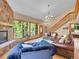 Inviting living room with a stone fireplace, staircase, and scenic views through large windows, creates a warm ambiance at 11768 Black Hawk Dr, Conifer, CO 80433