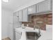 Cozy kitchen featuring grey cabinets, stainless steel sink, and brick backsplash at 4824 E Kentucky Ave # F, Denver, CO 80246