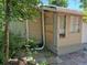 Side exterior view showing beige siding, a window, white trim, and overgrown foliage at 1272 N Ulster St, Denver, CO 80220