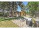 Spacious backyard with a stone fire pit, outdoor seating, and a view of a tan home surrounded by trees at 9416 Mcshane Ct, Parker, CO 80134