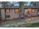 Exterior back view of tan home with brick chimney, surrounded by mature trees, and deck access stairs at 9416 Mcshane Ct, Parker, CO 80134