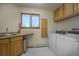 Functional laundry room with sink, washer, dryer, storage cabinets, and a bright window at 6300 Summer Star Ln, Golden, CO 80403