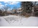 Wide backyard with a snow covered lawn and a wood fence and neighboring homes at 13486 Clayton St, Thornton, CO 80241