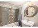 Updated bathroom with decorative mirror, shower with gray and tan accent tiles, and pedestal sink at 13486 Clayton St, Thornton, CO 80241