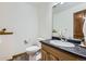 Powder room featuring a wood vanity with a black countertop, a toilet, and a decorative mirror at 538 Sawmill Creek Rd, Evergreen, CO 80439