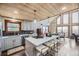 Modern kitchen with gray cabinetry, a white quartz island with seating, wood ceiling, and an open layout to the dining room at 538 Sawmill Creek Rd, Evergreen, CO 80439