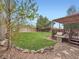 Backyard featuring a lawn, rock borders, trees, fence, deck, and grill at 8793 Cloverleaf Cir, Parker, CO 80134