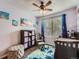 Bedroom featuring ocean themed decor, ceiling fan, a glider chair, and a dark wood crib, shelves, and ottoman at 8793 Cloverleaf Cir, Parker, CO 80134