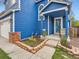 Close-up of the blue house featuring a porch, brick accents, flower garden, and walkway at 8793 Cloverleaf Cir, Parker, CO 80134
