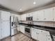 Well-equipped kitchen with stainless steel appliances, white cabinets, and black countertops for a modern touch at 8793 Cloverleaf Cir, Parker, CO 80134