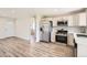 Open-concept kitchen featuring stainless steel appliances, white cabinets, and wood flooring at 16273 E Brown Pl, Aurora, CO 80013